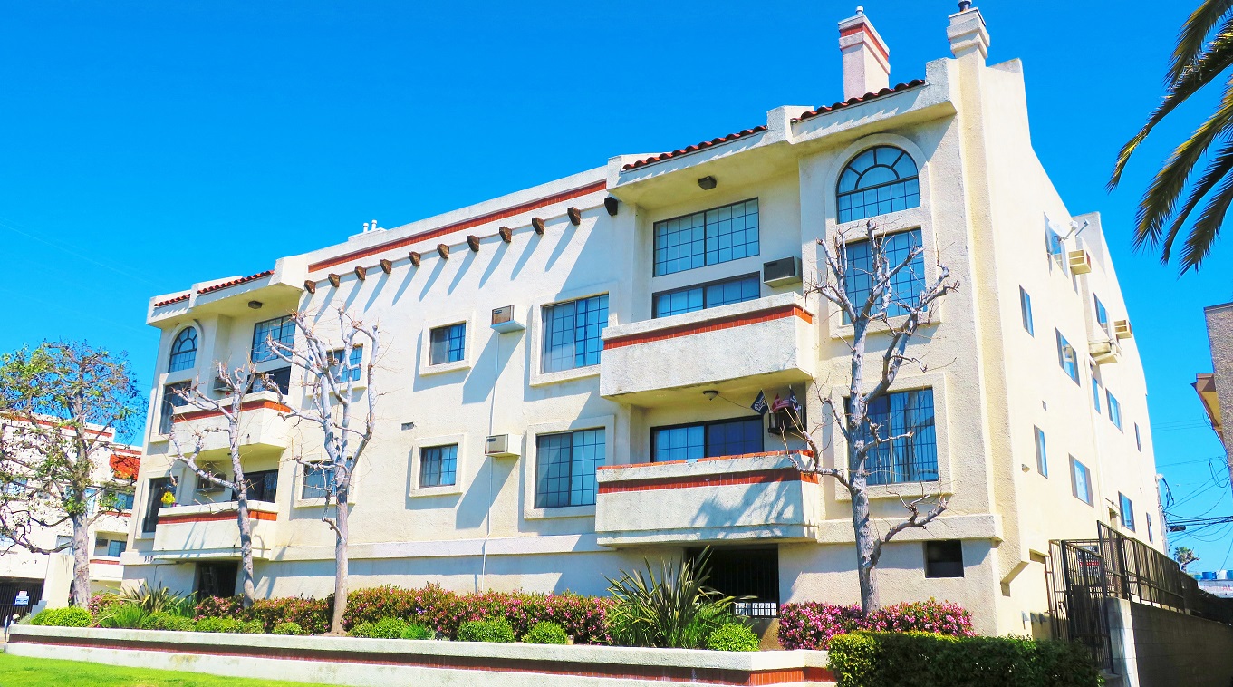 a white apartment building with balconies and a lawn